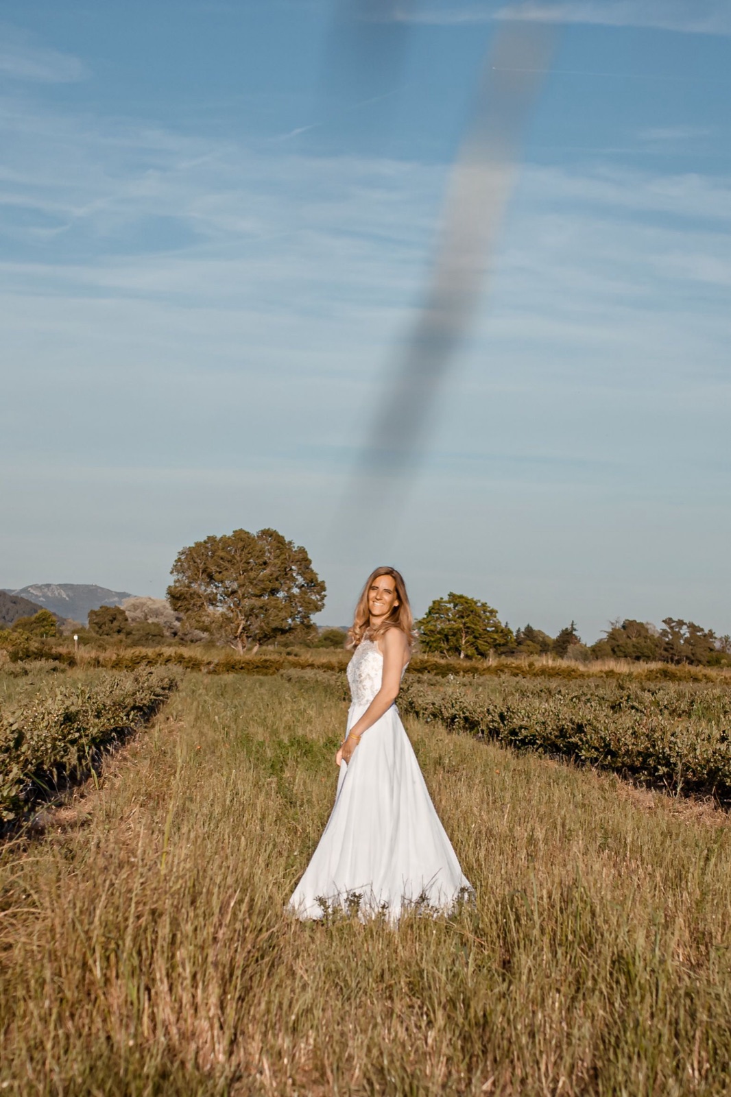 Mariée dans les champs du Domaine de la Myrtille, robe blanche dans les hautes herbes