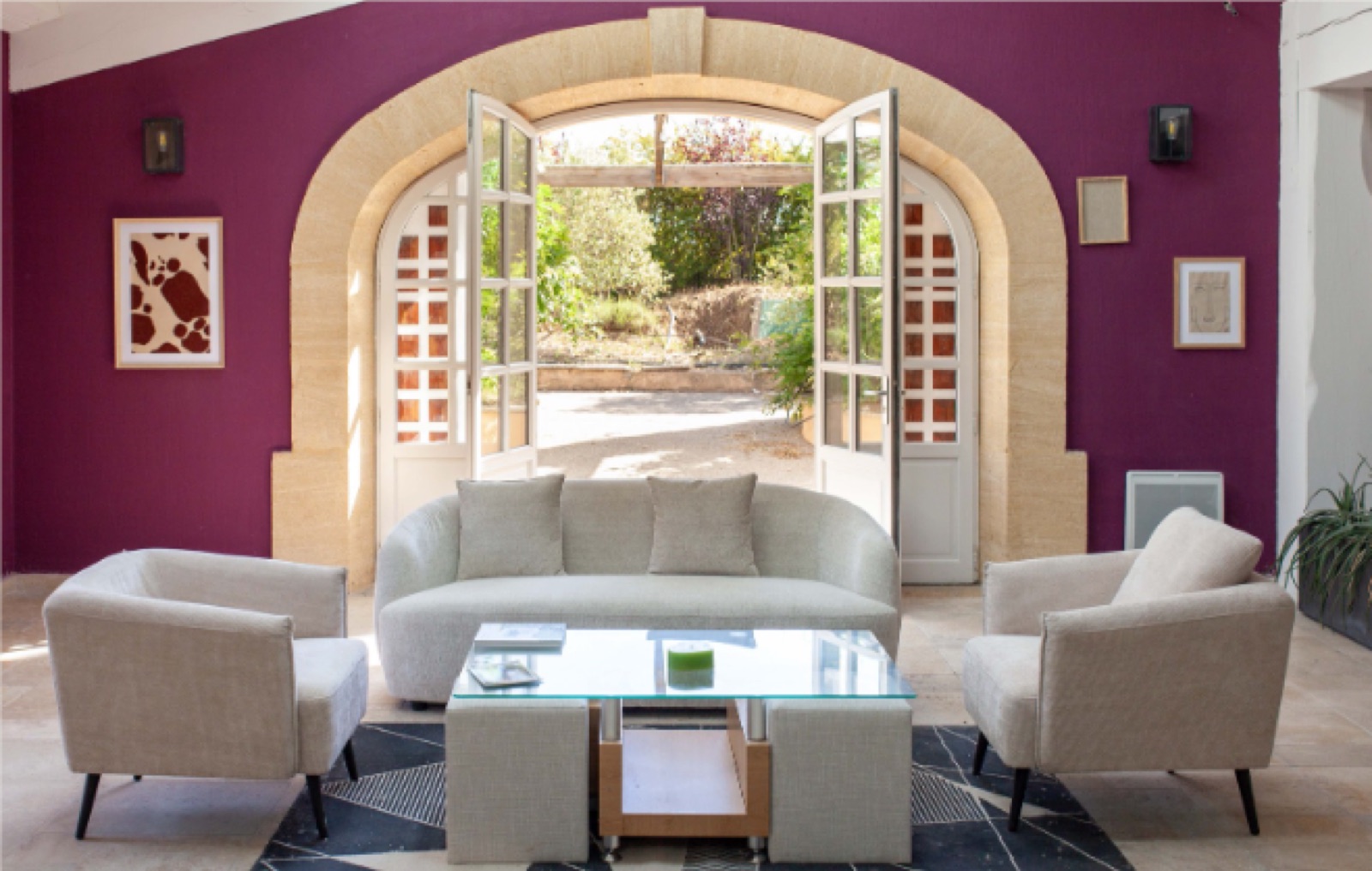 Salon aux murs prune avec porte cintrée ouverte sur le jardin, mobilier crème