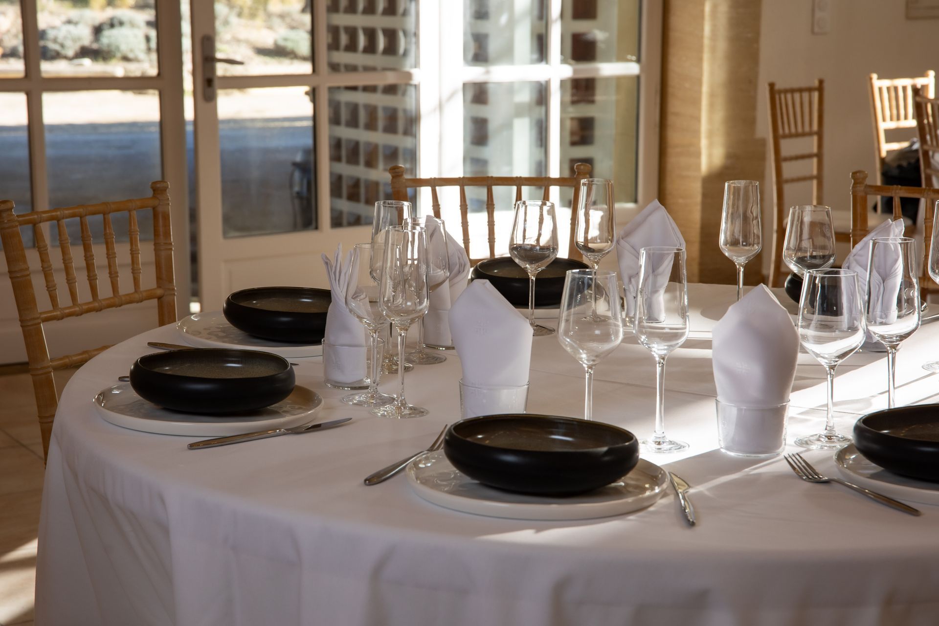 Table ronde dressée pour un dîner d’entreprise au Domaine de la Myrtille, nappe blanche et verres