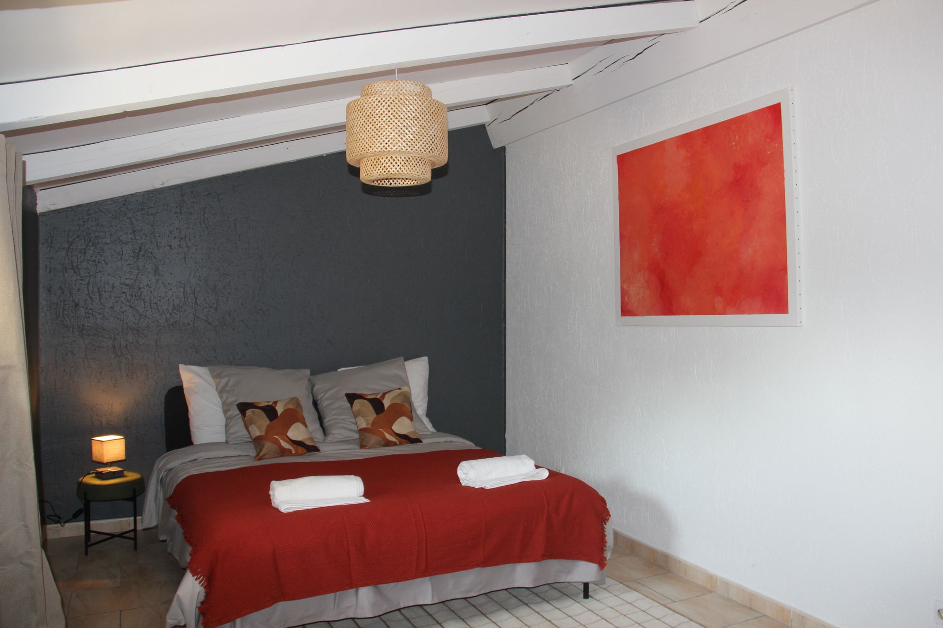 Chambre d’un appartement du domaine, mur gris foncé, lit et suspension tissée